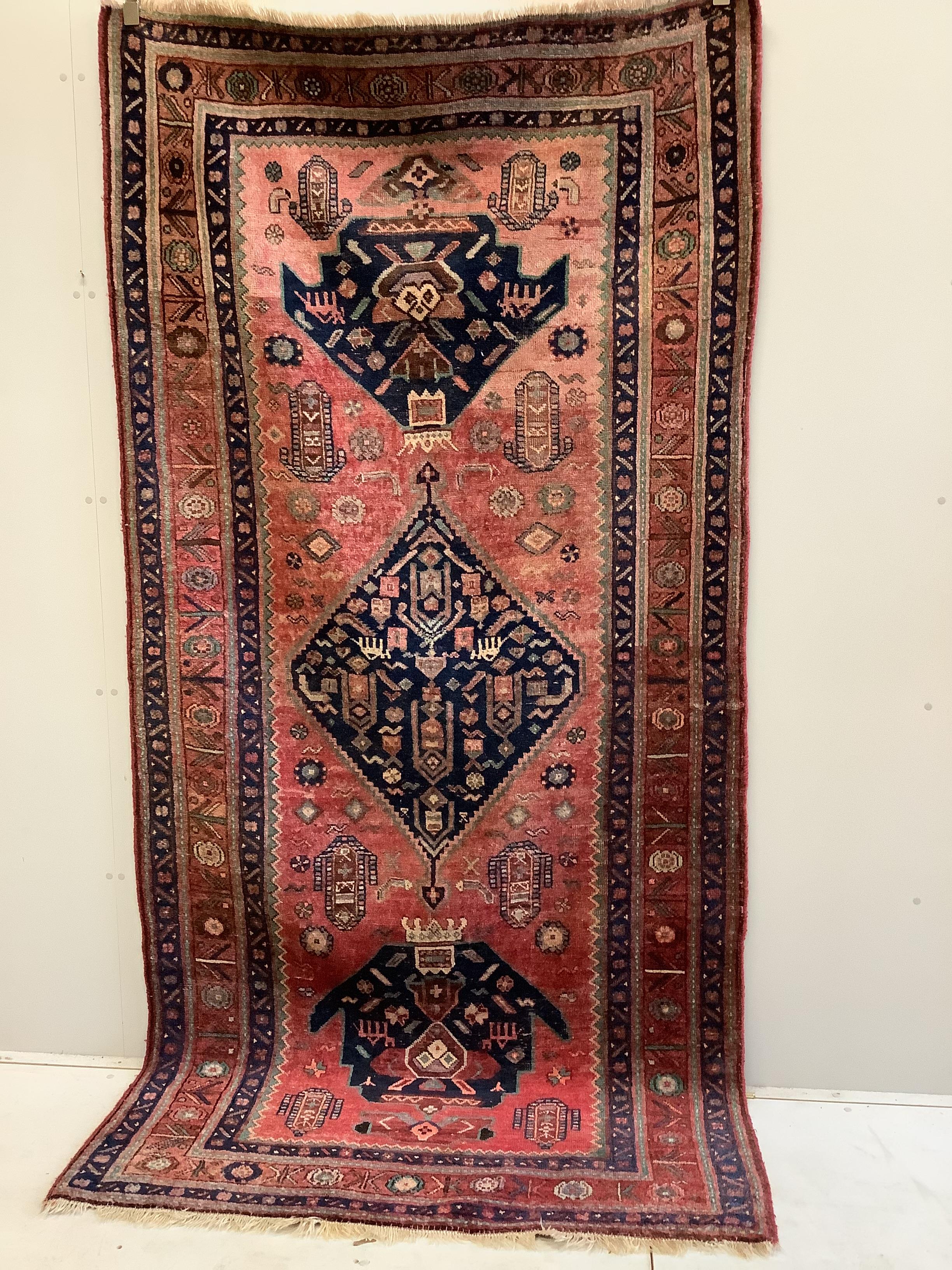An Heriz red ground medallion rug with triple medallions on a brick red ground, multi bordered, 280 x 137cm